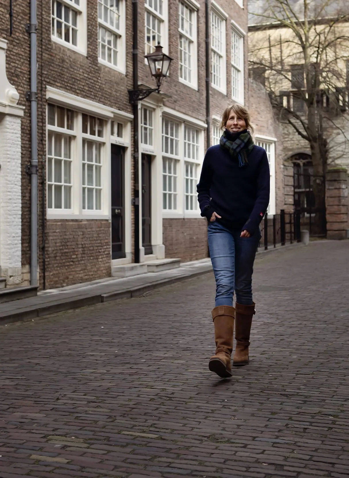 Mies Oude Avenhuis wandelt door een oude binnenstad met een geruite sjaal om